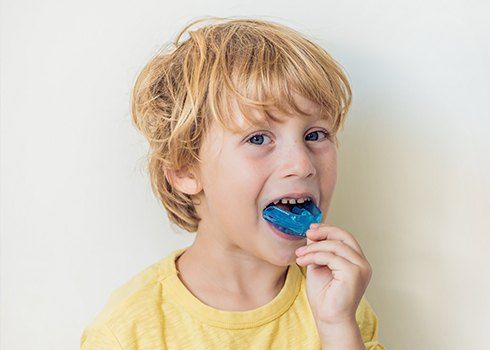 Child placing athletic mouthguard