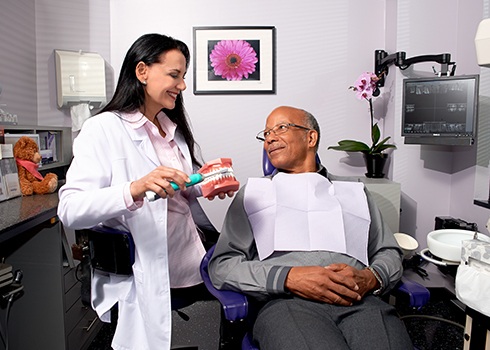 Dentist showing older male patient a smile model